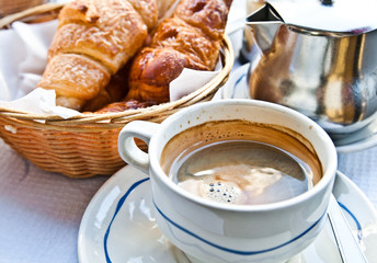 Breakfast with coffee and croissants in a basket on table