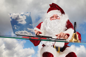 Santa Claus placing orders on his laptop and tablet-pc