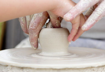 Artisan learning a child to make potter from white clay. - 35689892