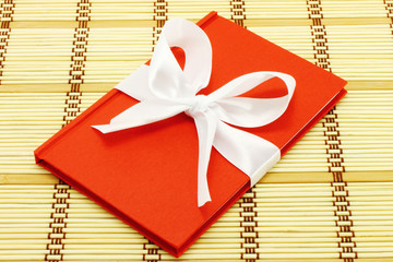 Notepad with white bow on a wooden background © rvlsoft