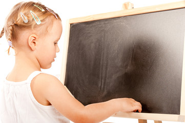 Little girl standing at the blackboard