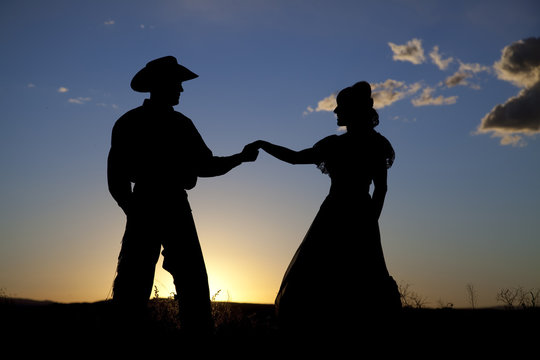 Cowboy couple silhouette holding hands