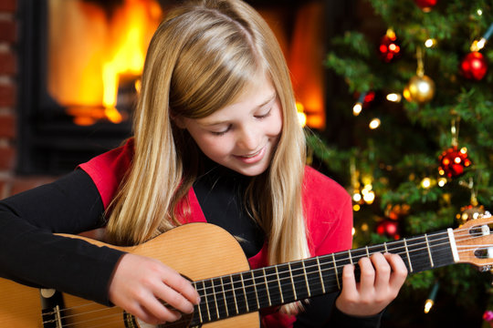 girl playing guitar on christmas eve