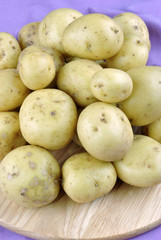 junge Kartoffeln gestapelt auf einem runden Holzbrett