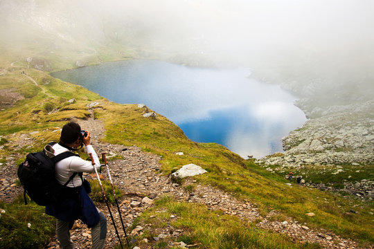 Hiker taking photos at Capra lake in Fagaras mountains, Romania