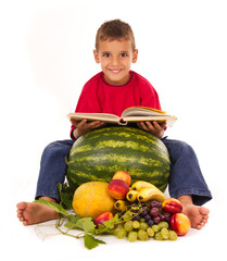 Fototapeta premium healthy boy reading a book and sit next to fresh fruit
