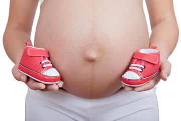 Pregnant woman hold in hand red baby boots