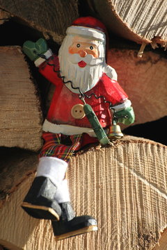 h&ouml;lzerner Weihnachtsmann sitzt auf Holzscheit