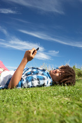 Teenage boy lying on grass with phone