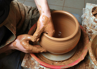 hands of a potter, creating an earthen jar on the circle