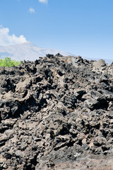 sharp hardened lava rocks with Etna on background