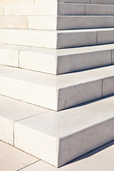White marble stairs outdoors with shadows on right side.