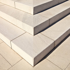White marble stairs outdoors with shadows on right side.
