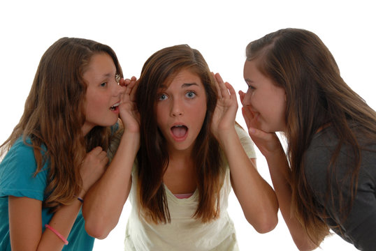 Teenage girls sharing secrets one is shocked others whispering.