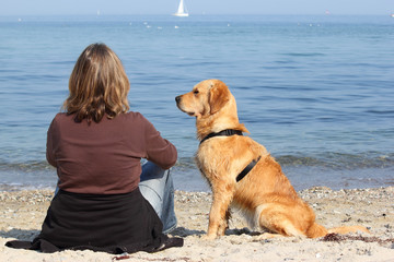 Golden Retriever mit Frau am Strand