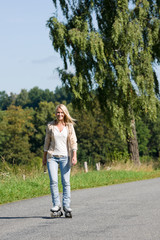 Inline skating young woman on sunny asphalt road