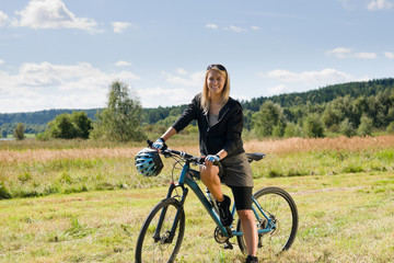 Fototapeta na wymiar Mountain biking young woman sportive sunny meadows