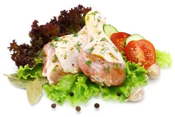 Raw chicken legs with vegetables on a white background