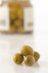 Delicious green olives with a full jar in background.