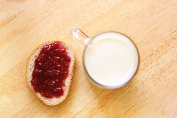 bread with jam and glass of milk on wooden table