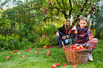 mother and daughter and a basket with red apples