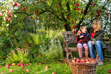 mother and daughter and a basket with red apples