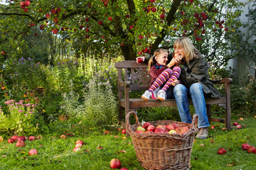 mother and daughter and a basket with red apples