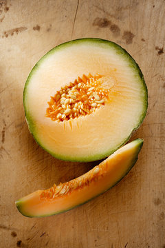 Cantaloupe melon slice and one half on wooden table