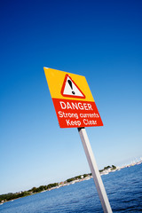 Danger Strong Currents Keep Clear warning sign against blue sky