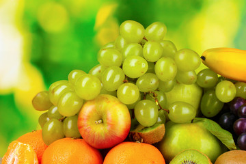 Ripe juicy fruits on wooden table on green background