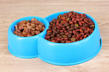 Dry cat food in bowls on wooden background