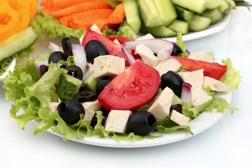 Greek salad on plate and sliced â€‹â€‹vegetables closeup