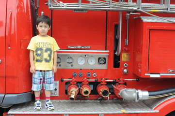 Young boy standing on a fire engine