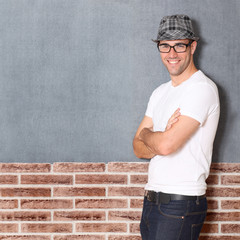 Trendy guy leaning on brick wall
