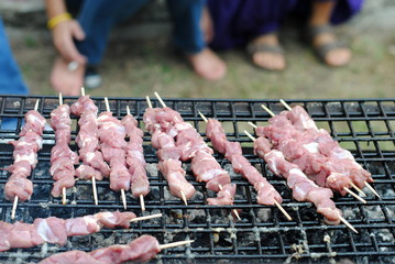 lamb kabobs grilled on skewers, and people foot on background