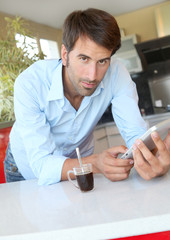 Man standing in kitchen with electronic tablet