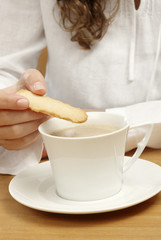 Femme trempant un biscuit dans une tasse de café au lait