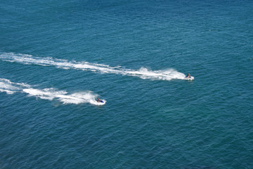 Aerial shot of two jet skiers racing against a blue sea
