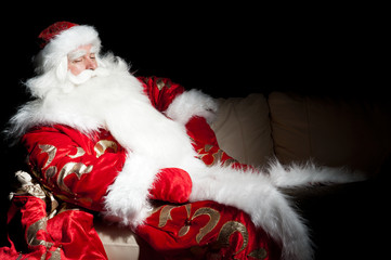 Santa sitting with a sack indoor at dark night room