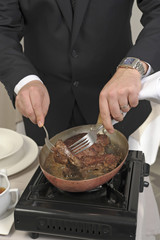 Retourner la viande pour la préparation du steak sauce au poivre sur le guéridon