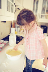 Obraz na płótnie Canvas Happy child girl making muffins in kitchen