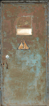 Old rusty door with "high voltage" sign on it
