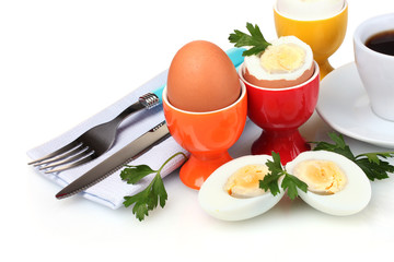 Boiled eggs in bright stands and cutlery isolated on white
