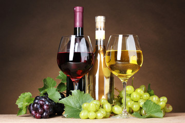 Glasses of wine, bottles and grapes on yellow background