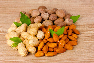 nutmeg, peanuts and almonds on wooden background