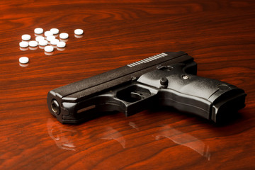Nine millimeter gun on surface with white pills