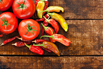 Assortment of chilli peppers and tomato on a rustic wooden table
