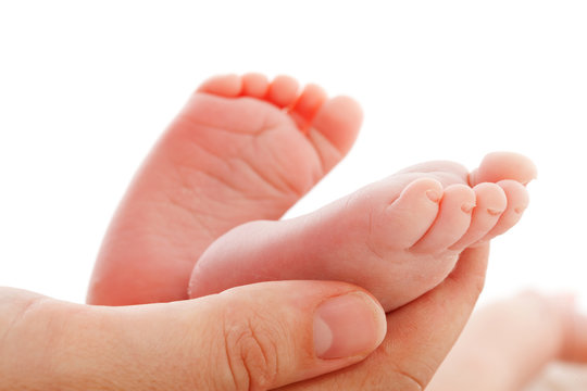 Mother holding newborn baby feet over white background