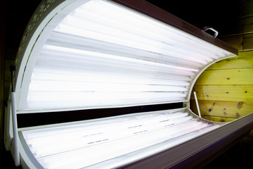 Open tanning bed with lit white bulbs