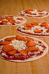 Four uncooked pepperoni and cheese tortilla pizzas